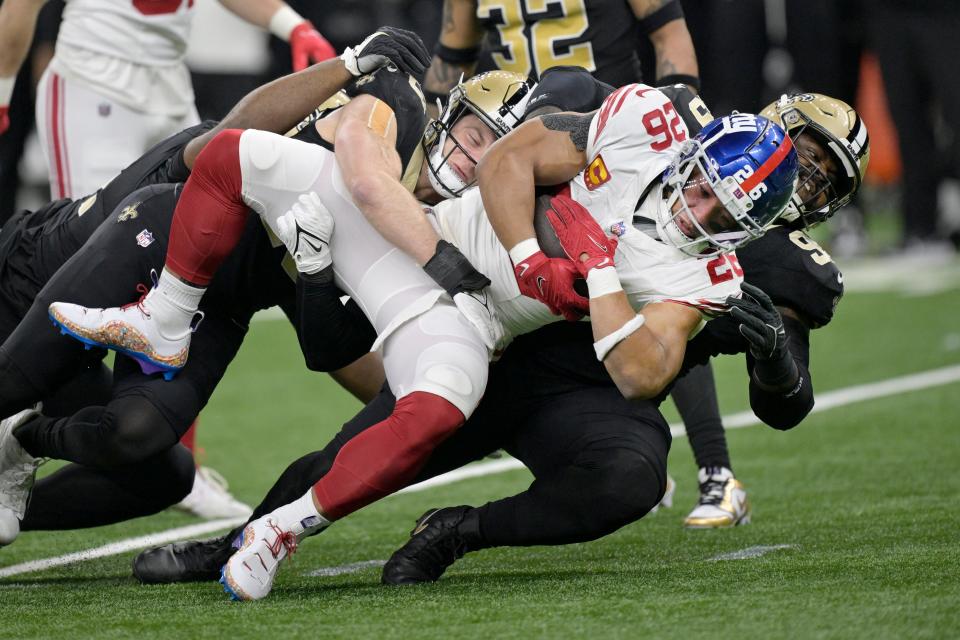 New York Giants running back Saquon Barkley (26) struggles for yardage as New Orleans Saints defensive tackle Khalen Saunders, right, defends during the first half of an NFL football game Sunday, Dec. 17, 2023, in New Orleans. (AP Photo/Matthew Hinton)