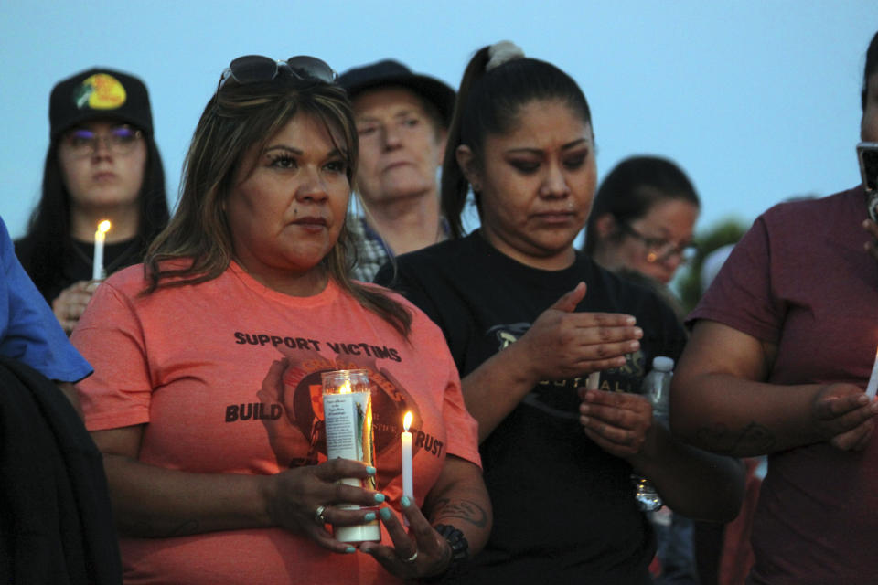 Community members hold candles during a prayer vigil at Hills Church, Monday, May 15, 2023, in Farmington, N.M. Authorities said an 18-year-old man roamed through the community firing randomly at cars and houses Monday, killing three people and injuring six others including two police officers before he was killed. (AP Photo/Susan Montoya Bryan)