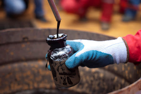 A worker collects a crude oil sample at an oil well operated by Venezuela's state oil company PDVSA in Morichal, Venezuela, July 28, 2011. REUTERS/Carlos Garcia Rawlins/Files