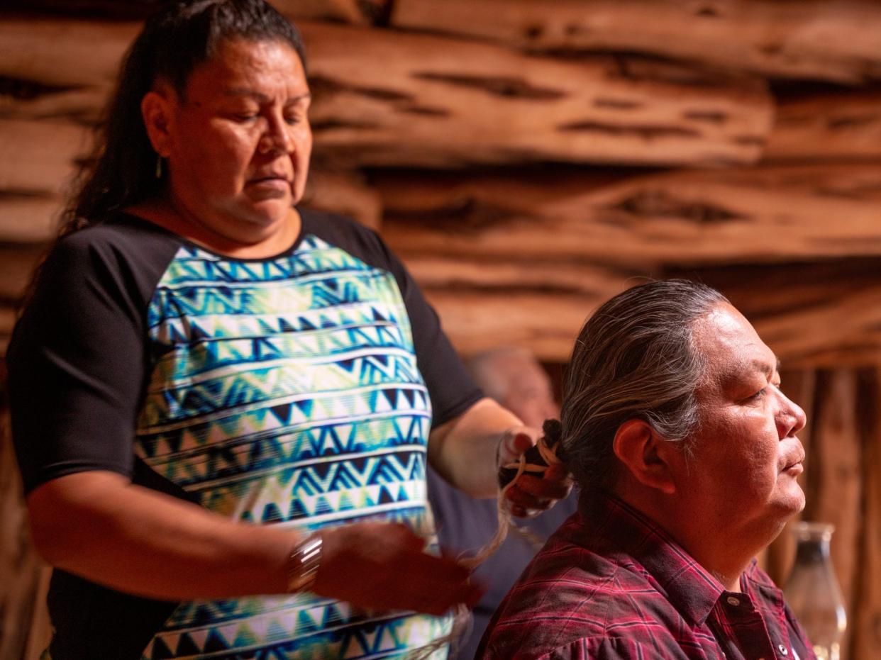 Navajo woman helping her husband braid his hair in Monument Valley, Arizona, Navajo Tribal Park