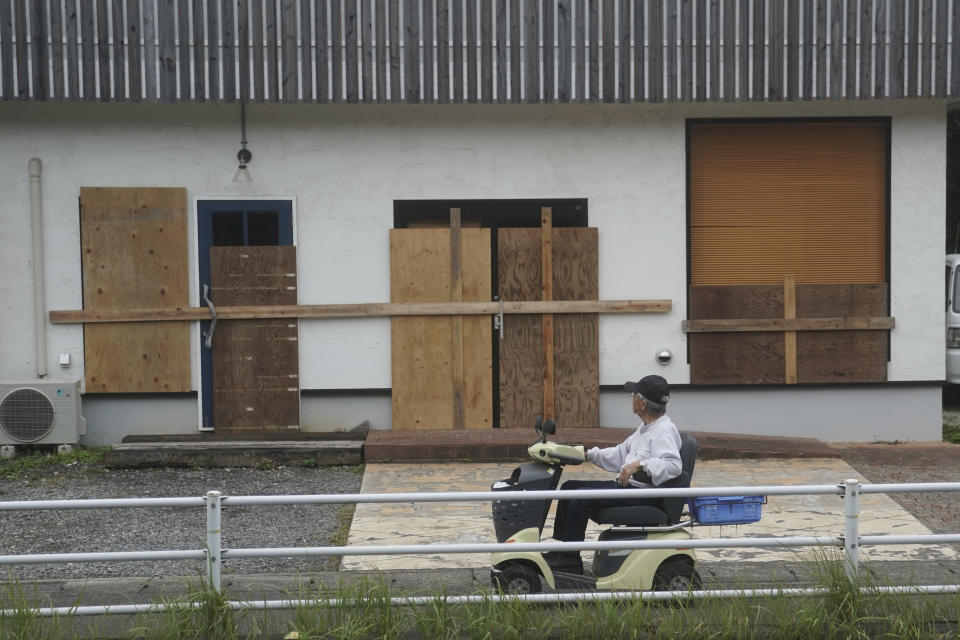 A man looks at a shop, protected by wood boards, as Typhoon Hagibis approaches in town of Kiho, Mie Prefecture, Japan Friday, Oct. 11, 2019. A powerful typhoon was forecast to bring 2 feet of rain and damaging winds to the Tokyo area this weekend, and Japan's government warned people Friday to stockpile supplies and evacuate before it's too dangerous. (AP Photo/Toru Hanai)