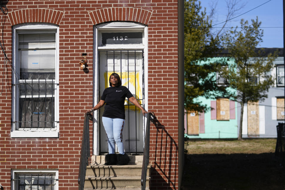 Angela Banks poses for a photograph in front of the house she used to rent, Wednesday, Feb. 15, 2023, in Baltimore. In 2018, Banks was told by her landlord that Baltimore officials were buying her family's home of four decades, planning to demolish the three-story brick rowhouse to make room for an urban renewal project aimed at transforming their historically Black neighborhood. Banks and her children became homeless almost overnight. Banks filed a complaint Monday asking federal officials to investigate whether Baltimore's redevelopment policies are perpetuating racial segregation and violating fair housing laws by disproportionately displacing Black and low-income residents. (AP Photo/Julio Cortez)