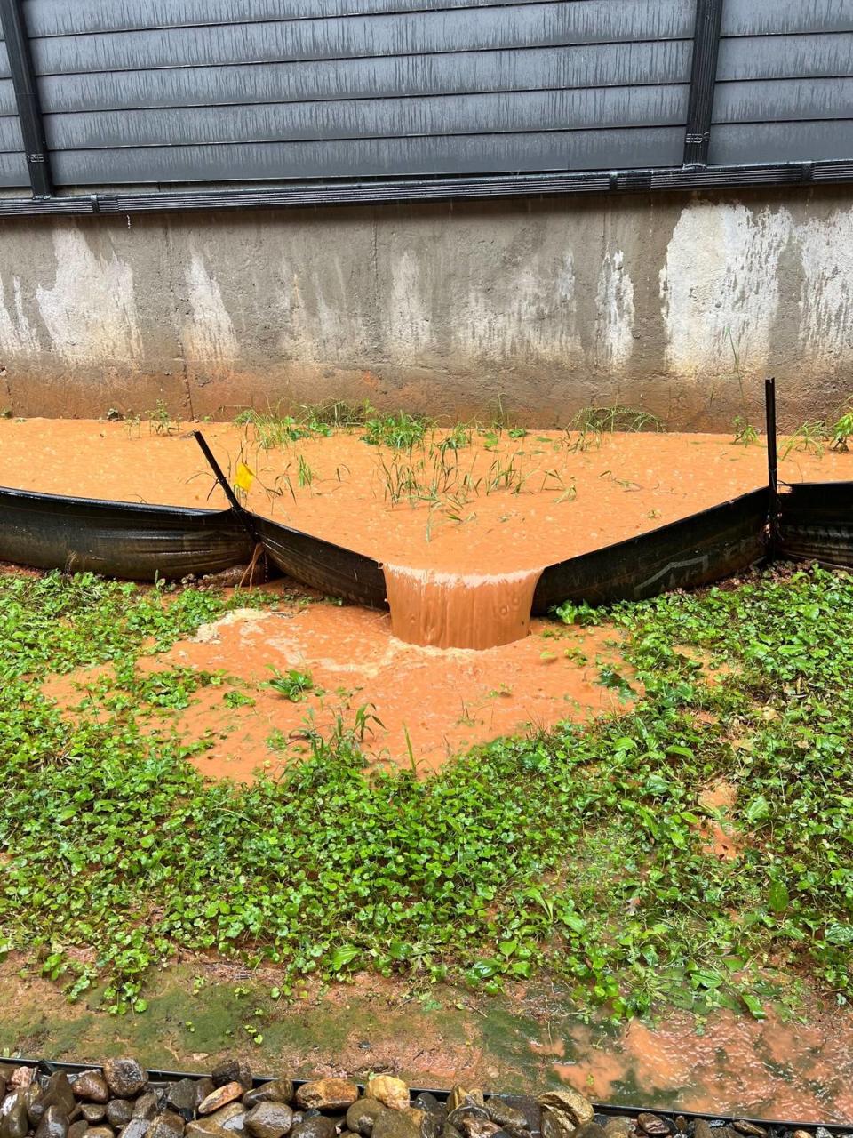 Water spills over a barrier installed to help prevent erosion along Coxe Avenue in Charlotte.
