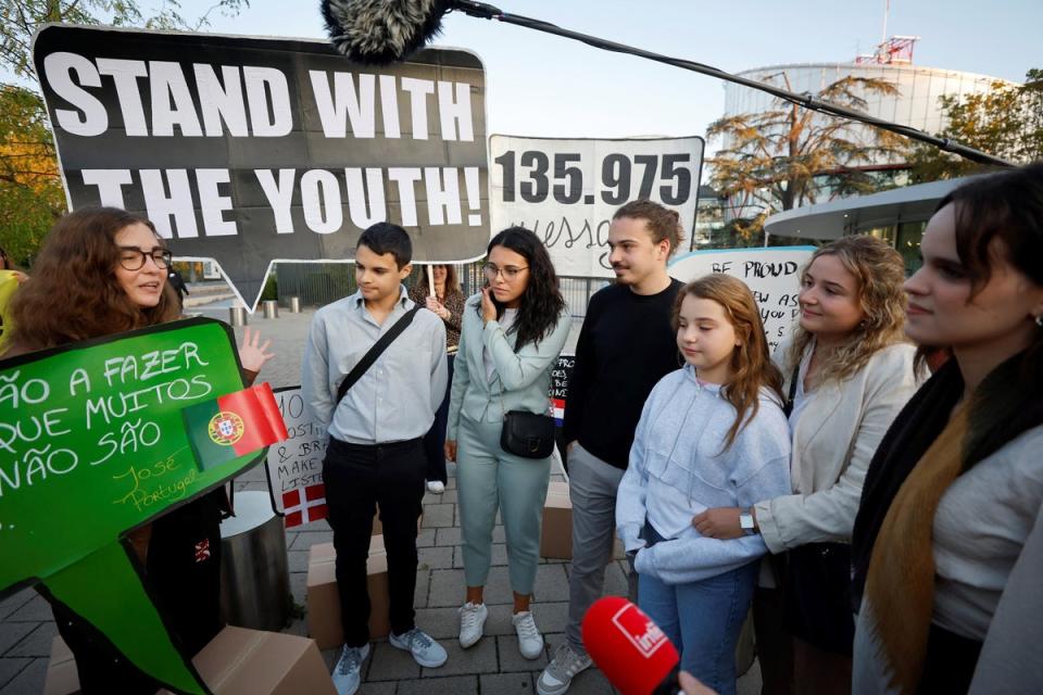 Young Portuguese citizens hold placards as they arrive at the European Court of Human Rights (ECHR) for a hearing in a climate change case involving themselves against 32 countries, in Strasbourg, eastern France (AFP via Getty Images)