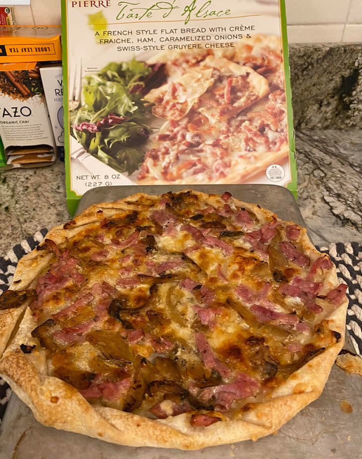 A cooked Tarte d'Alsace next to the box.