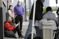 FILE - In this Saturday, May 16, 2020, file photo, Glen Buhlmann, lower left, fills out a job application during a walk- and drive-up job fair in Seattle for clothing maker Outdoor Research's new line of face masks and other personal protection equipment the company has started manufacturing due to the coronavirus pandemic. U.S. employers likely rehired several million more workers in June, thereby reducing a Depression-level unemployment rate, but the most up-to-date data suggests that a resurgent coronavirus will limit further gains. (AP Photo/Ted S. Warren, File)