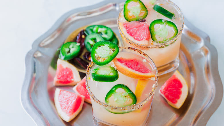 Two glasses of spicy mezcal margarita with garnishes