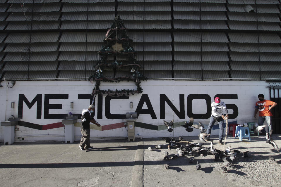 A man feeds pigeons at the entrance of the Municipal Market in Mejicanos, a district of San Salvador, El Salvador, Sunday, April 4, 2021. This working-class district was a stronghold of the Farabundo Martí National Liberation Front, FMLN, party but during the Feb. 28, elections it voted for New Ideas, the party of President Nayib Bukele. Himself an outcast from the FMLN. (AP Photo/Salvador Melendez)