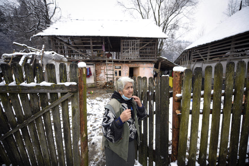 An elderly woman adjusts her mask while watching Valeriu Nicolae deliver basic goods to families with school children in Nucsoara, Romania, Saturday, Jan. 9, 2021. The rights activist has earned praise for his tireless campaign to change for the better the lives of the Balkan country’s poorest and underprivileged residents, particularly the children. (AP Photo/Andreea Alexandru)