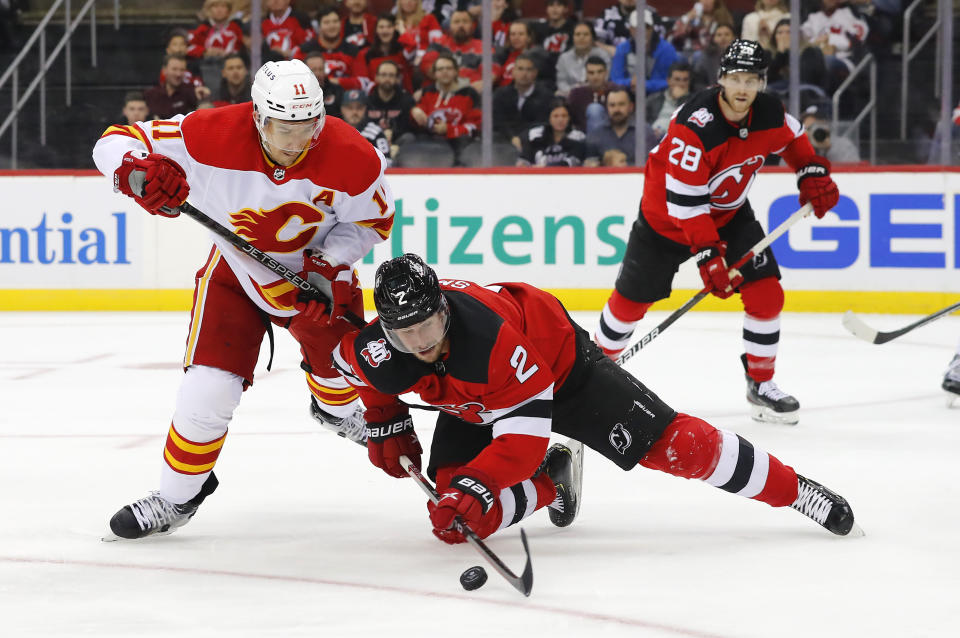 New Jersey Devils defenseman Brendan Smith (2) plays the puck against Calgary Flames center Mikael Backlund (11) during the second period of an NHL hockey game, Tuesday, Nov. 8, 2022, in Newark, N.J. (AP Photo/Noah K. Murray)