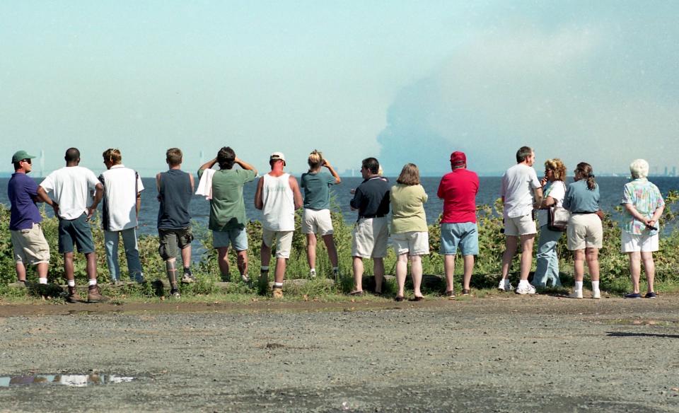 Spectators at the Atlantic Highlands Municipal Marina witness smoke rising from the World Trade Center in Lower Manhattan on September 11, 2001.