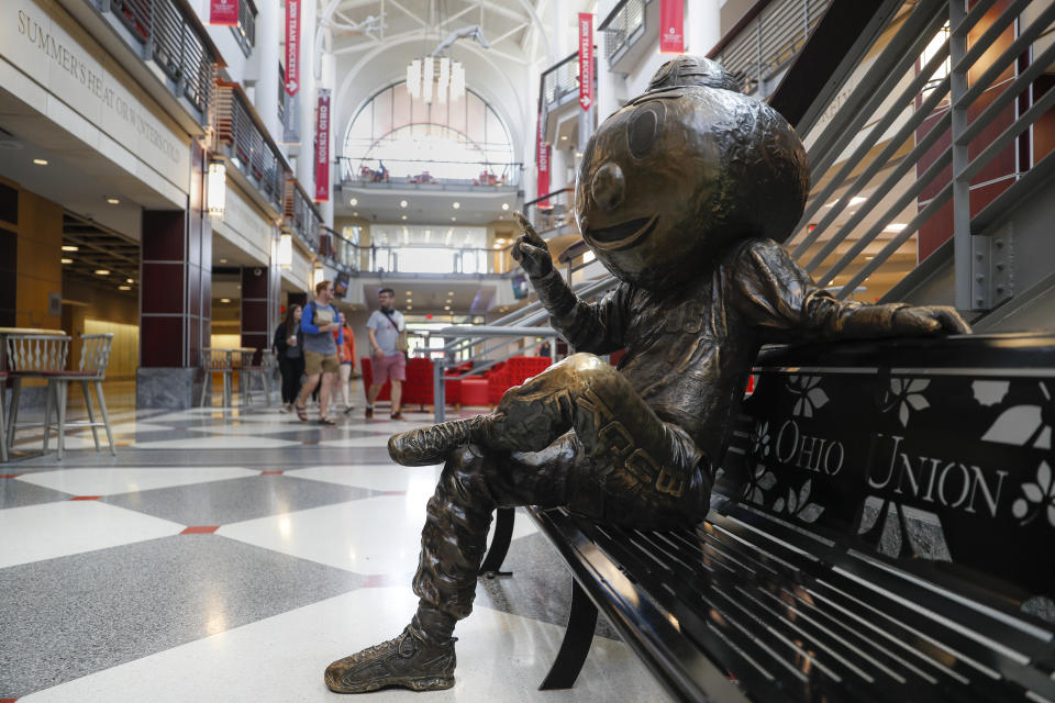 FILE - In this May 18, 2019 file photo pedestrians pass through The Ohio State University's student union in Columbus, Ohio. Mike Drake, the president of The Ohio State University says he'll retire from that role next year. Drake's five-year tenure at one of the nation's largest universities has included strategic successes, such as record numbers for the school in applications, graduates, research expenditures and donor support. But it also has been marred by scandals involving the university's marching band, a prominent football coach and a former team doctor accused of widespread sexual abuse. (AP Photo/John Minchillo, File)