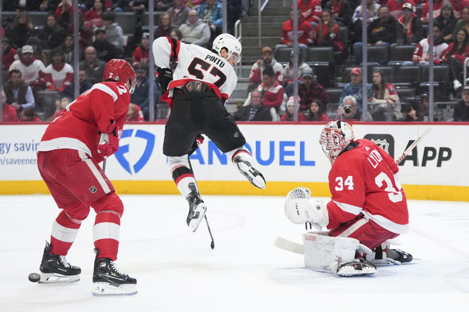 Ottawa Senators center Shane Pinto (57) jumps out of the way of a shot on Detroit Red Wings goaltender Alex Lyon (34) as Detroit Red Wings' Olli Maatta (2) defends in the first period of an NHL hockey game Wednesday, Jan. 31, 2024, in Detroit. (AP Photo/Paul Sancya)