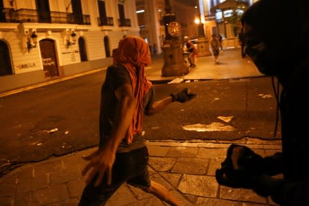 A demonstrator throws a stone at the police during clashes in a protest calling for the resignation of Governor Ricardo Rossello in San Juan