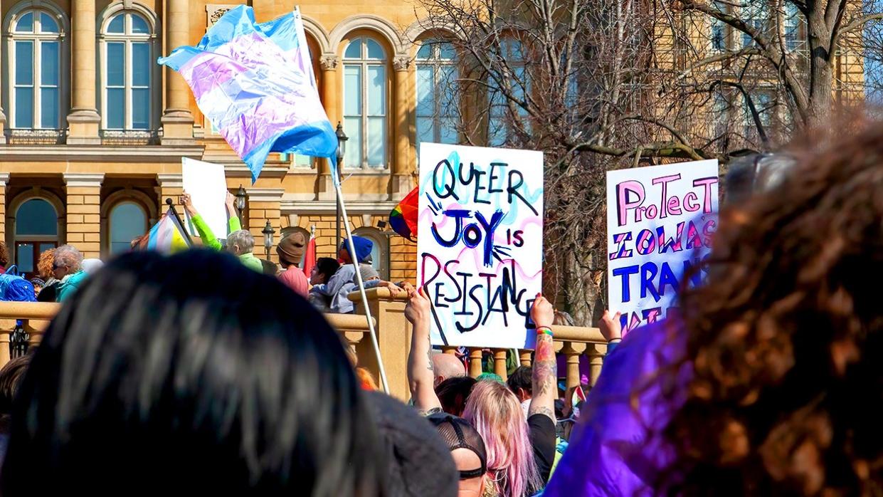 Des Moines Iowa March 2023 queer joy protect trans signs transgender pride flag at Rally to Resist where two thousand people rallied outside Iowa State Capitol in support of LGBTQ rights and against antiLGBTQ bills moving through state legislature