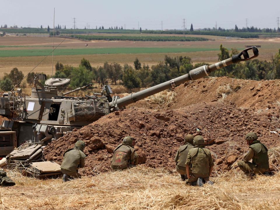 Israeli soldiers take cover at their position near Sderot in southern Israel on the border with the Hamas-controlled Gaza Strip during shellingMenahem Kahana/AFP via Getty Images