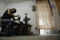 Blanca Evangelista Villada uses a machine to iron decorative designs onto face masks which she sells for 15 pesos each (about 65 cents) to supplement the family's income after her tee-shirt business was declared non-essential during the coronavirus pandemic, in San Gregorio Atlapulco, Xochimilco, Mexico City, Wednesday, July 29, 2020. In the span of a month, Evangelista and her husband buried his parents and an aunt who died of COVID-19, and fell ill themselves along with their daughters but recovered. (AP Photo/Rebecca Blackwell)