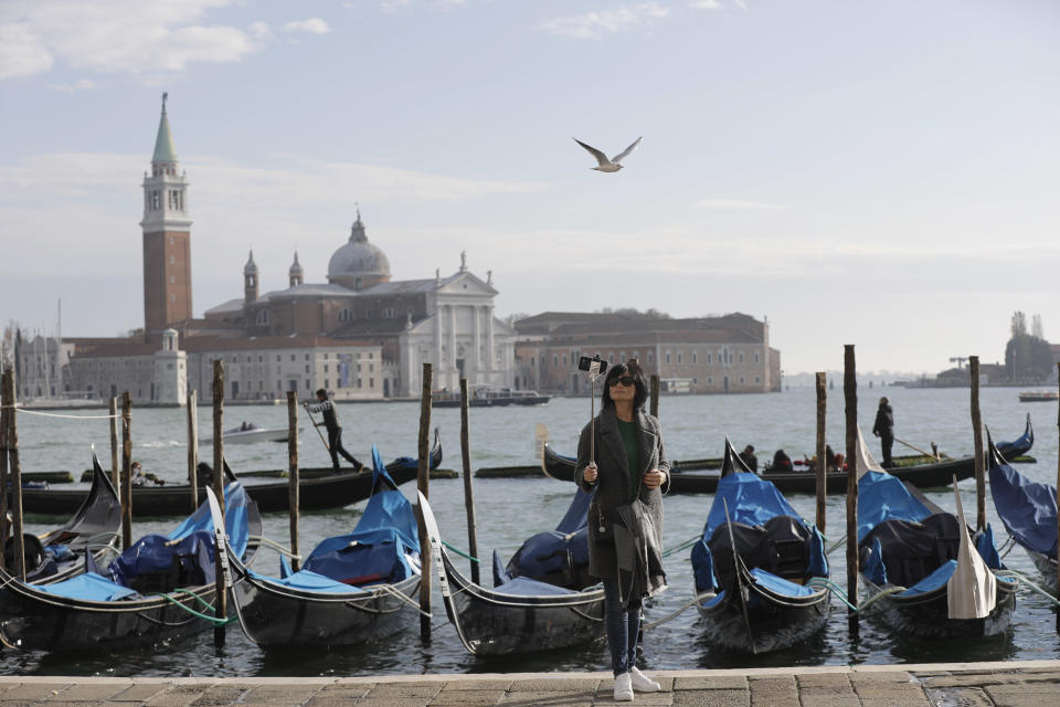 FILE - A tourist takes a selfie in St. Mark's Square in Venice, Italy, Nov. 12, 2016. Starting in January, Venice will oblige day-trippers to make reservations and pay a fee to visit the historic lagoon city. On many days, the heart of Venice is overwhelmed by visitors, who often far outnumber residents. Venice officials on Friday unveiled new rules for day-trippers, which go into effect on Jan. 16, 2023. (AP Photo/Luca Bruno, File)