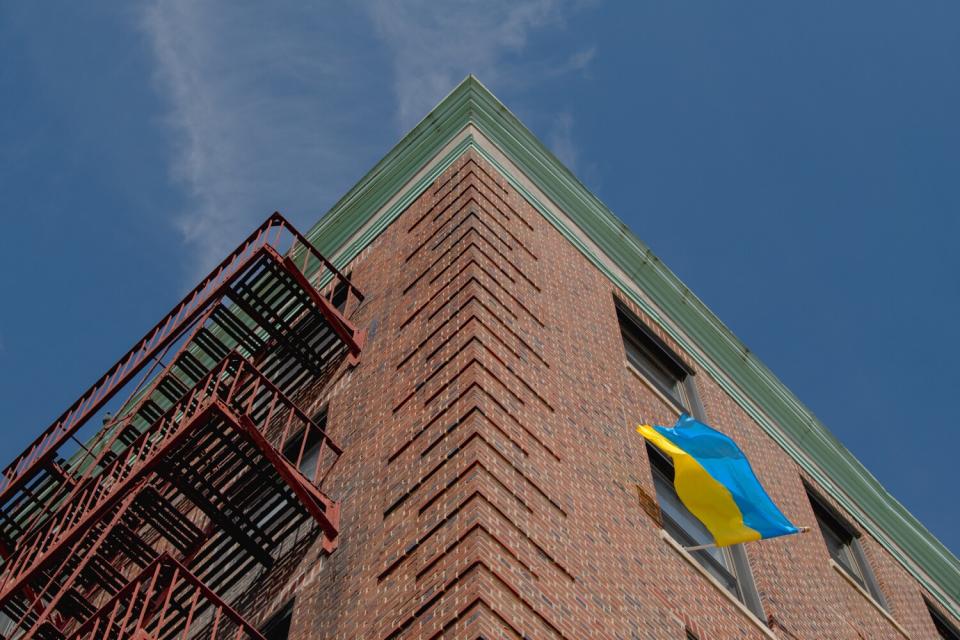 A blue-and-yellow Ukrainian flag hangs from a window.