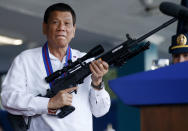 FILE - Philippine President Rodrigo Duterte jokes to photographers as he holds an Israeli-made Galil rifle at Camp Crame in suburban Quezon city northeast of Manila, Philippines on April 19, 2018. An International Criminal Court chief prosecutor, Karim Khan, said on June 24, 2022 that he has sought authorization from the court to resume an investigation into drug killings as a possible crime against humanity, from Nov. 1, 2011 when Duterte was still a Davao mayor to March 16, 2019. (AP Photo/Bullit Marquez, File)