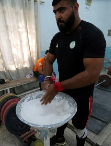 Ali Hamza, a member of the Iraqi national weightlifting team, chalks his hands while exercising during a training session at Badra weightlifting club
