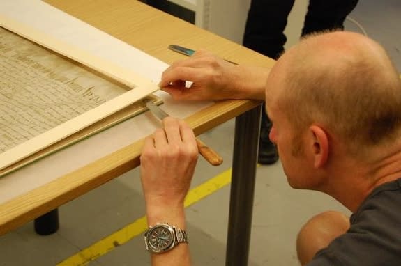 Conservator Gavin Moorhead removes the damaged Magna Carta from its 1970s-era mounting.
