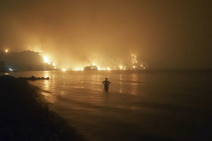 A man watches as wildfires approach Kochyli beach near Limni village on the island of Evia, about north of Athens, Greece on Aug. 6, 2021. (AP Photo/Thodoris Nikolaou)