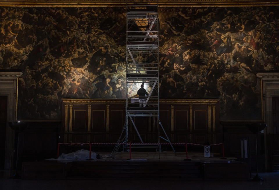 Restorer Alberto Marcon inspects the 7,45x24,65-meter oil on canvas 'Il Paradiso' completed in 1592 by Venetian painters Jacopo Robusti, also known as Tintoretto, and his son Domenico in the Maggior Consiglio Hall inside Palazzo Ducale in Venice, northern Italy, Wednesday, Dec. 6, 2022. The Doge's Palace, the heart of the political life of the Venetian Republic for centuries, is undergoing a major reconnaissance of its conservation status by the Fondazione Musei Civici of the municipality of Venice that includes the urgent restoration of its paintings and infrastructures, which is expected to be completed in the summer of 2023. (AP Photo/Domenico Stinellis)