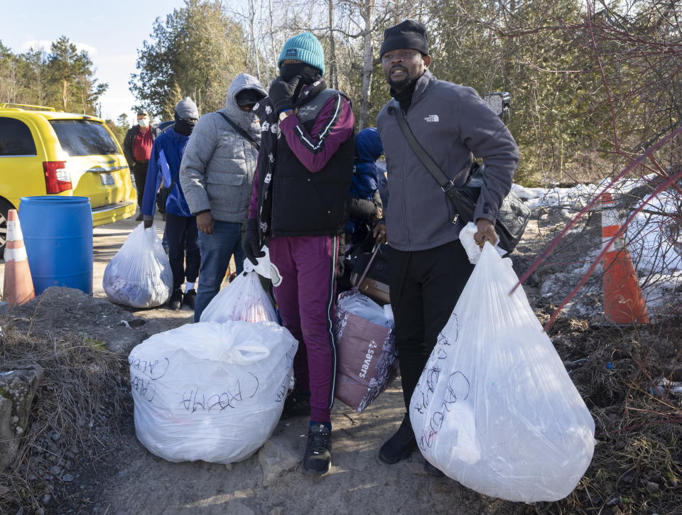 Asylum seekers cross the border at Roxham Road from New York into Canada on Friday, March 24, 2023 in Champlain, N.Y. The irregular border crossing will be closed permanently tonight at midnight. (Ryan Remiorz/The Canadian Press via AP)
