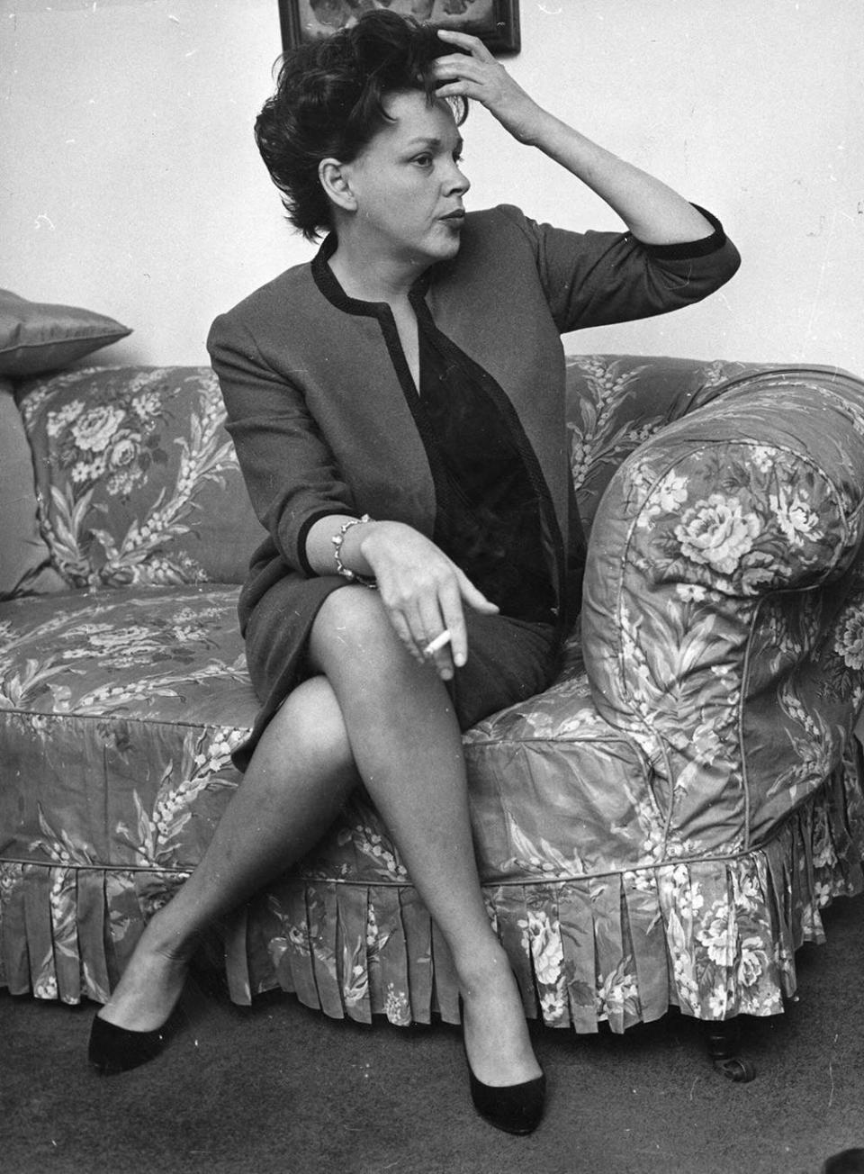 Judy Garland sitting on a couch and stroking her hair