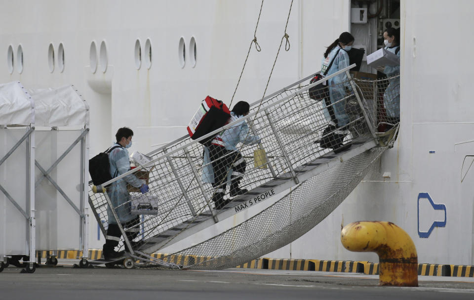 People wearing protective clothing head for the Princess Diamond which 70 passengers and a crew have been found positive in a new type coronavirus test at Daikoku Wharf in Yokohama, Kanagawa Prefecture.