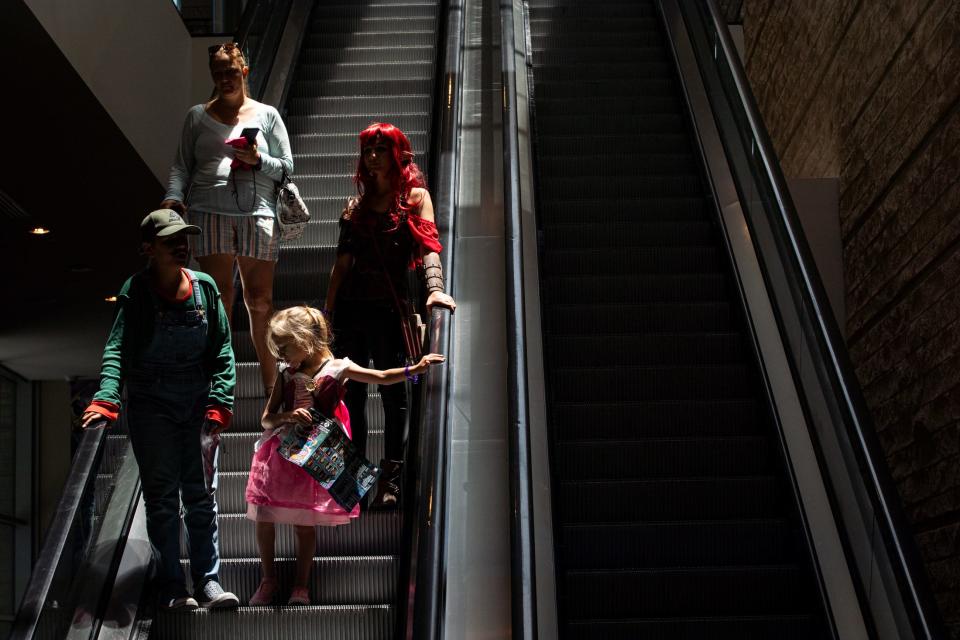 Cosplayers ride an escalator at Corpus Christi Comic Con in the American Bank Center on Friday, July 28, 2023.