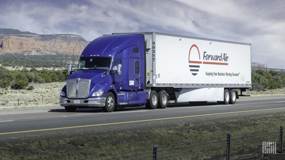 A sleeper cab pulls a white Forward Air trailer on a highway