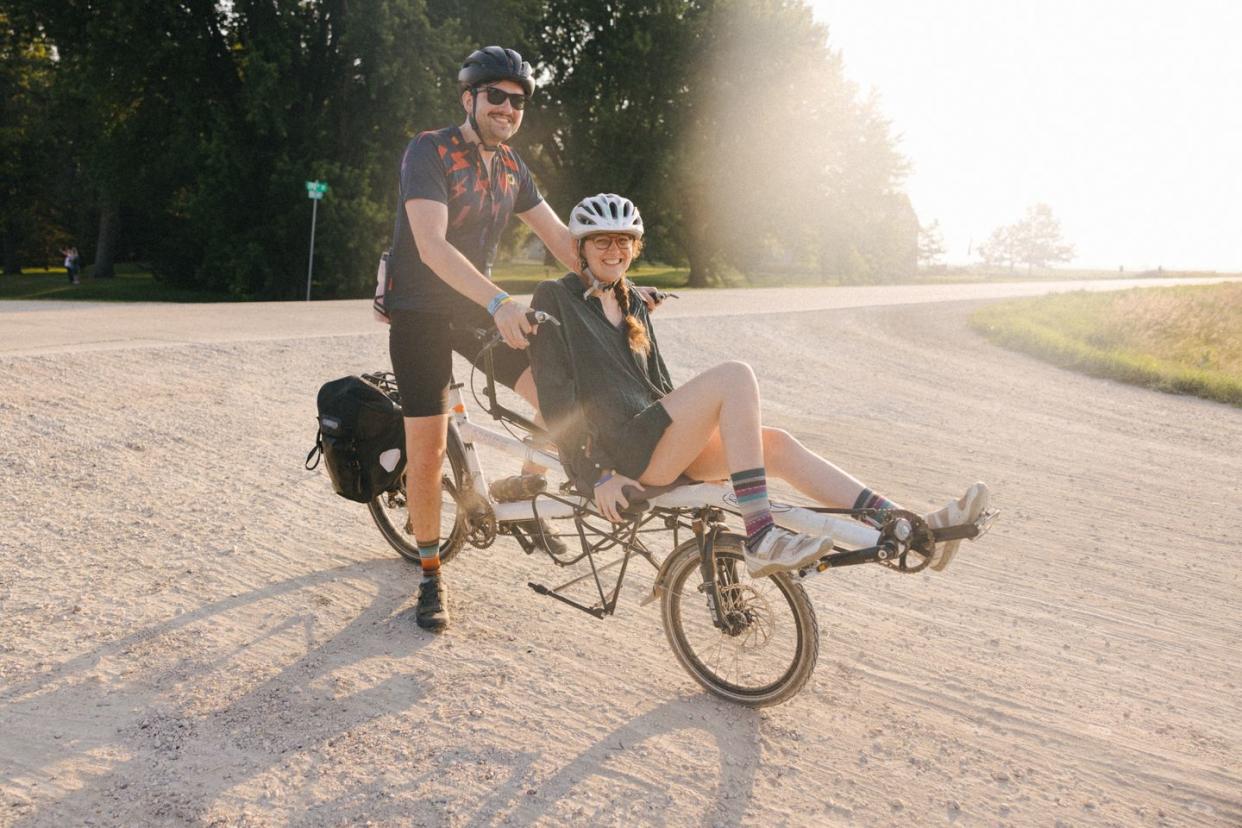 two cyclists on a gravel road ride a tandem bike