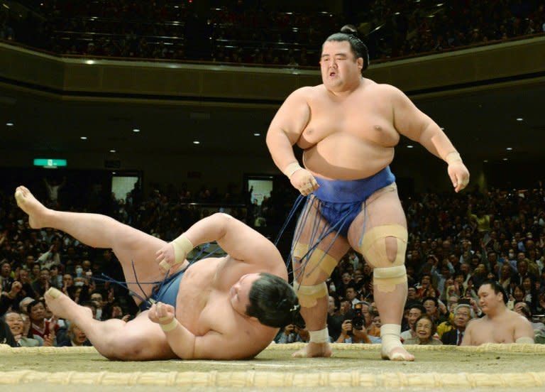 Ozeki, or champion, Kotoshogiku (R) throws down fellow ozeki-ranked wrestler Goeido (L) during their final bout in the New Year Grand Sumo tournament in Tokyo on January 24, 2016