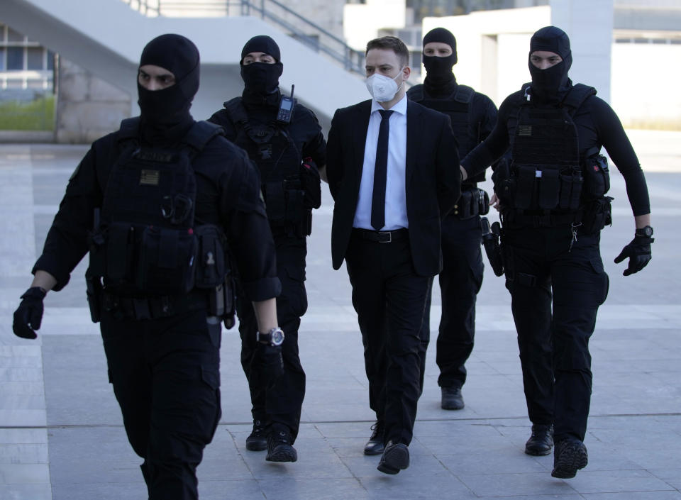 Babis Anagnostopoulos, a Greek pilot and flight instructor, center, escorted by policemen arrives at a court in Athens, Greece, Monday, May 16, 2022. A verdict is expected Monday in the case of the helicopter pilot who confessed to murdering his young British-Greek wife Caroline Crouch and faking a robbery to mislead police in May 2021. (AP Photo/Thanassis Stavrakis)