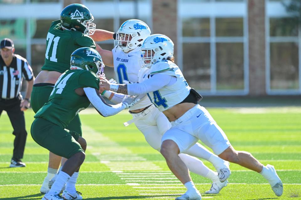 University of West Florida defensive lineman Jacob Dorn (0) and linebacker Walker Robinson (44) push up against Delta State defenders during the Argos' 49-14 loss at Delta State in the first round of the NCAA Division II playoffs in Cleveland, Mississippi, on Saturday, Nov. 18, 2023.