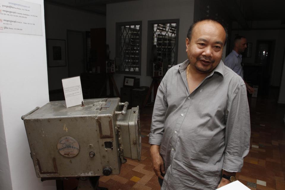 In this photo taken Monday, Feb. 17, 2014, Cambodian film director Rithy Panh stands next to an old film camera placed in his office in Phnom Penh, Cambodia. In his latest movie, the 51-year-old filmmaker focuses for the first time on his personal story of loss and tormented survival of a genocide by the Khmer Rouge regime. It is a poetic and highly original film - with no actors, just little clay figures - that may be his most celebrated yet. "The Missing Picture" won an award at last year's Cannes Film Festival and is up for Best Foreign Language Film at the Oscars this weekend, marking the first time a Cambodian film has been nominated for an Academy Award. (AP Photo/Heng Sinith)