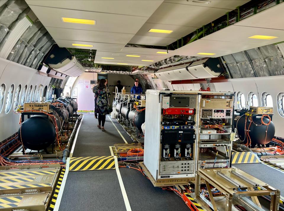 Inside the 777X cabin with black barrels and computer systems.