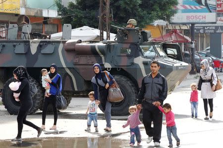 Civilians walk past a Lebanese army soldier patrolling on an armored vehicles after being deployed to tighten security following clashes between Lebanese soldiers and Islamist gunmen in Tripoli, northern Lebanon, October 27, 2014. REUTERS/Mohamed Azakir