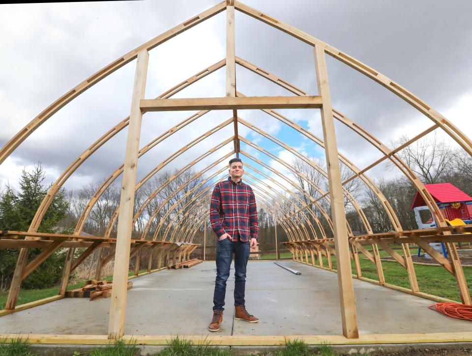 James Laska, who owns Manchester Micro Farm with his wife Deana, stands inside the framework of the 36 x 18 foot greenhouse he is constructing on April 4 in New Franklin.