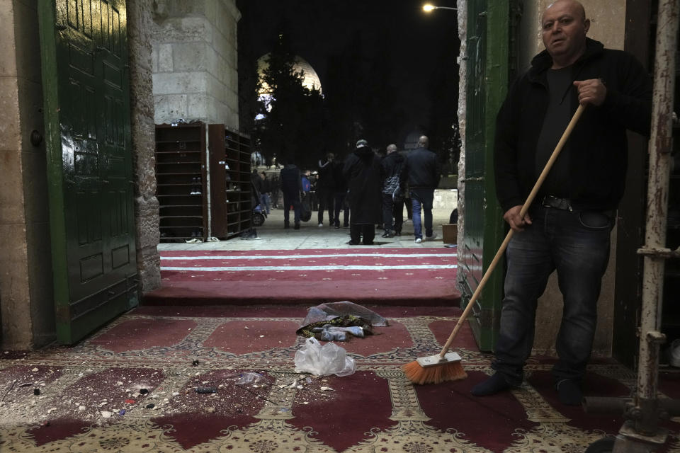 A Palestinian worshipper sweeps debris after a raid by Israeli police at the Al-Aqsa Mosque compound in the Old City of Jerusalem, Wednesday, April 5, 2023. Palestinian media reported police attacked Palestinian worshippers, raising fears of wider tension as Islamic and Jewish holidays overlap.(AP Photo/Mahmoud Illean)