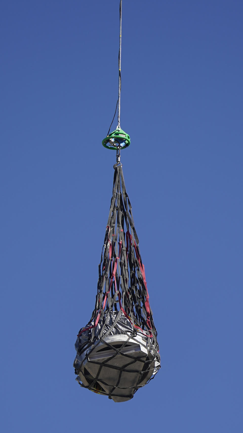 A helicopter delivers a space capsule carrying NASA's first asteroid samples on Sunday, Sept. 24, 2023, to a temporary clean room at Dugway Proving Ground, in Utah. The Osiris-Rex spacecraft released the capsule following a seven-year journey to asteroid Bennu and back. (AP Photo/Rick Bowmer, Pool)