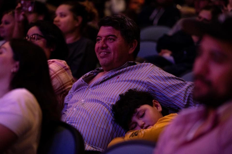 Oliver Martinez sleeps against father Jorge Martinez's side while his sister, a Webb Elementary School student, participates in an American Sign Language concert at Veterans Memorial High School, on Friday, Dec. 16, 2022, in Corpus Christi, Texas.