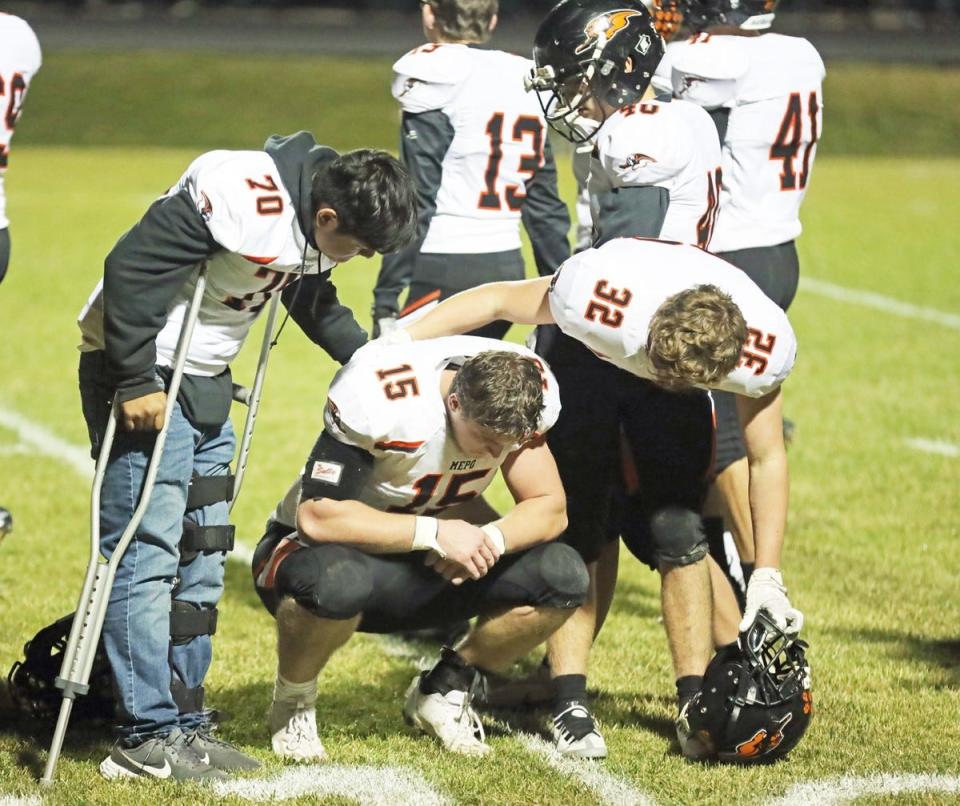 Mediapolis’ Jacob Wirt (70) and Alton Wonderlijk (76) console senior Cole Lipper after the Bulldogs' heartbreaking overtime loss to Sigourney-Keota on Friday.