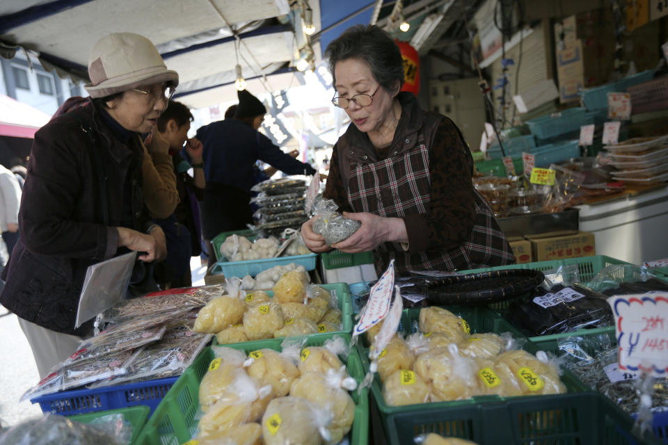 A shop clerk, right, explains a product to a customer, left, at a dry fish store at a fish market in Tokyo, Tuesday, April 8, 2014. Japan's central bank has refrained from expanding its ultra-loose monetary policy despite a sales tax hike, saying the economy is recovering moderately. The Bank of Japan's policy statement Tuesday was the first since an April 1 increase in the sales tax, to 8 percent from 5 percent, that is expected to stall economic growth in coming months as consumers adjust to higher costs. (AP Photo/Eugene Hoshiko)