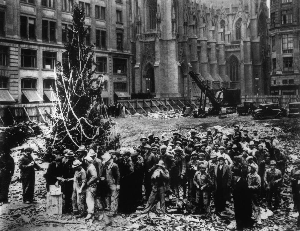 Construction workers line up for pay beside the first Rockefeller Center Christmas tree in New York in this 1931 file photo. The Christmas tree went on to become an annual tradition and a New York landmark. St. Patrick's Cathedral is visible in the background on Fifth Avenue.