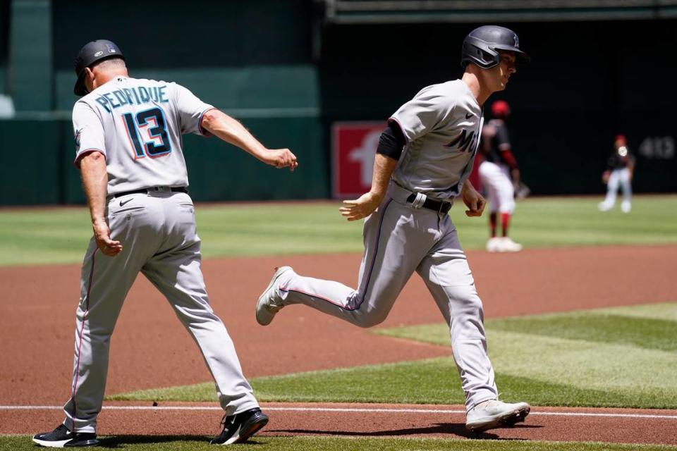 Miami Marlins’ Joey Wendle, right, slaps hands with Marlins third base coach Al Pedrique (13) as Wendle rounds the bases after hitting a two-run home run against the Arizona Diamondbacks during the first inning of a baseball game Wednesday, May 11, 2022, in Phoenix.