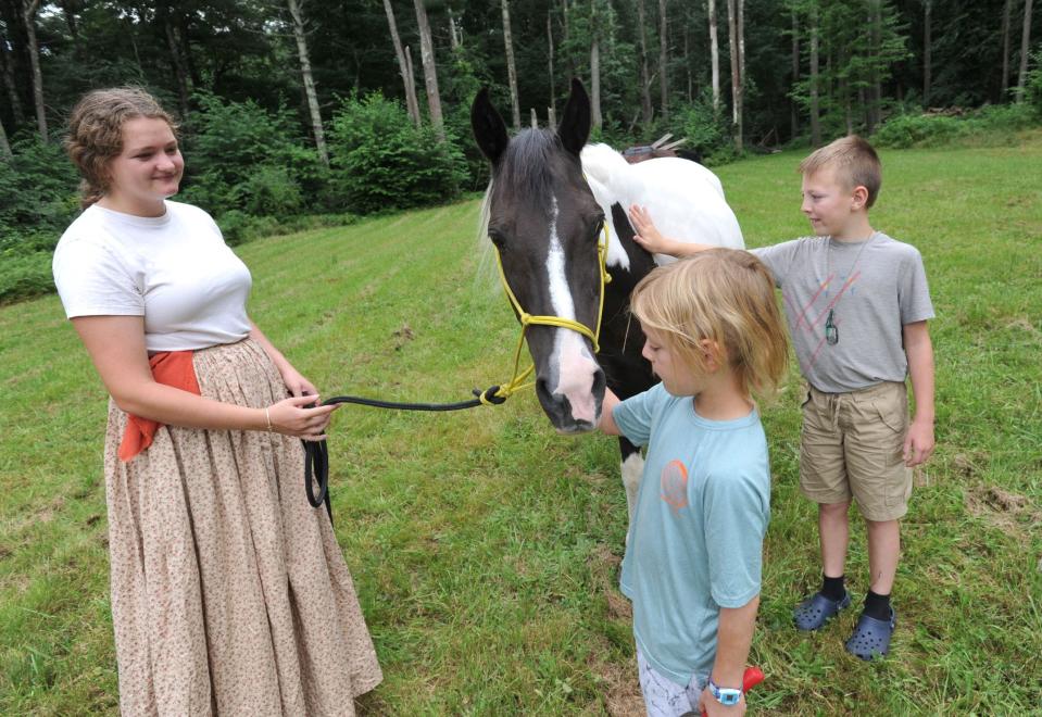 Abigail Lambert, of Norwell, left, looks on as Patrick Garafalo, 8, center, and his brother, Eddie Garafalo, 10, right, of Norwell, give some attention to cookies and cream during the Stetson Heritage Day, Saturday, Aug. 19, 2023.