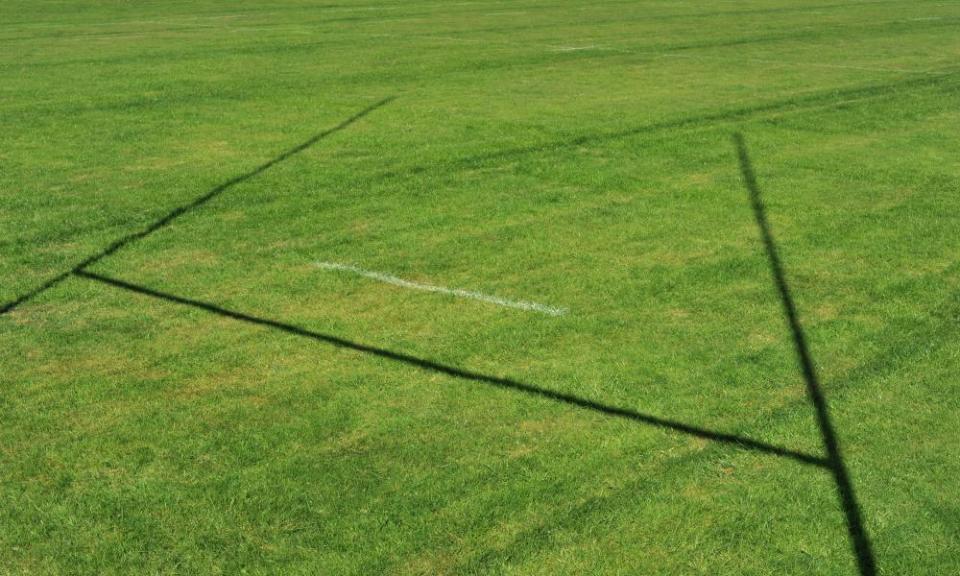 Shadow of rugby posts on rugby field